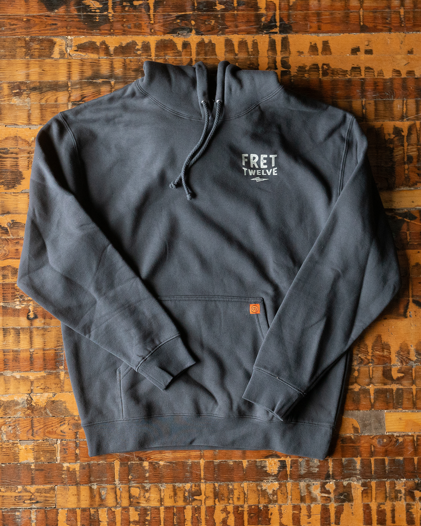 This heavy weight asphalt hoodie by FRET12 features a screen printed graphic of the String Thing carrying a road case.